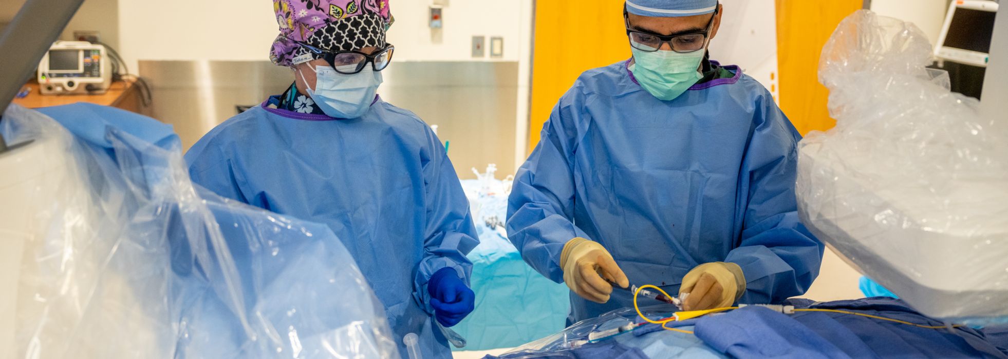 Doctors in blue scrubs perform a procedure in the UW cath lab.
