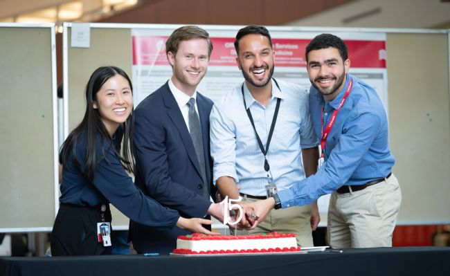 Four internal medicine residents shared in the ceremonial cutting of a cake in celebration of the 15th anniversary of Research Day. L-R: Jeanette Liou, MD, chief resident; Clayton Skogman, MD, PG-3; Bikrum Chahal, MD, PG-3; and Ahmed El Shaer, MBBS, chief resident.