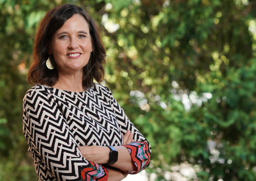 Photo of Carey Gleason, PhD, in front of a background of green leaves.