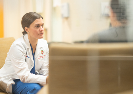 Dr. Kruser talking with a patient, as seen through a translucent glass window 