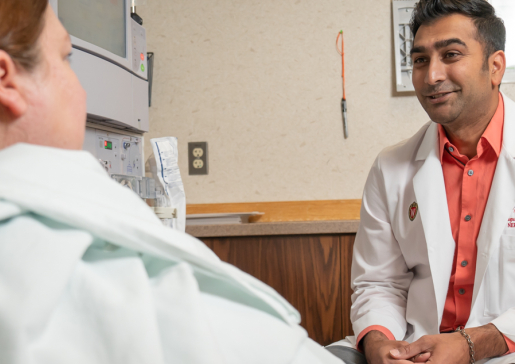 Dr. Roy Jhagroo talks to a patient at the bedside at University Hospital