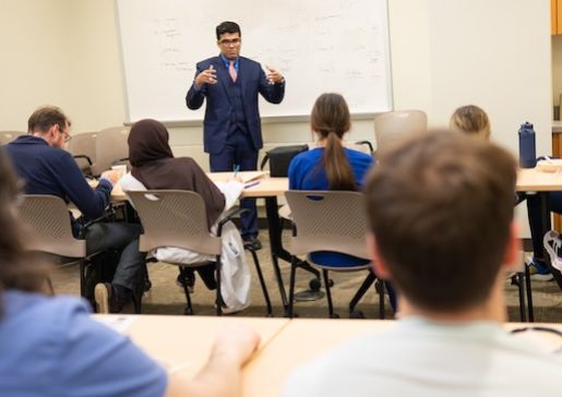 Dr. Farhan Raza stands in front of a white board teaching nephrology fellows