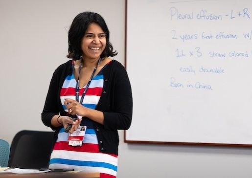 Former chief resident and current Hematology and Oncology fellow Caroline Burkey, MD, lectures at a white board during Morning Report