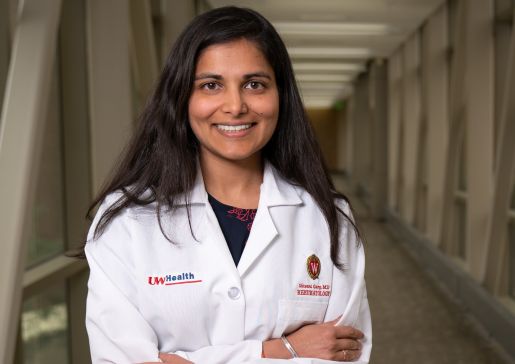 Dr. Shivani Garg in her white coat, standing in a hallway.