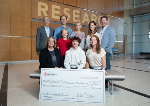 Photo of some of the Dotzauer family and friends, with Heather Dotzauer at lower right, gathered for a check presentation with Dr. Hector Valdivia, at top left, representing the Division of Cardiovascular Medicine.